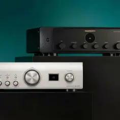 Dwa wzmacniacze audio: srebrny Denon i czarny Marantz, na czarnych podstawkach.